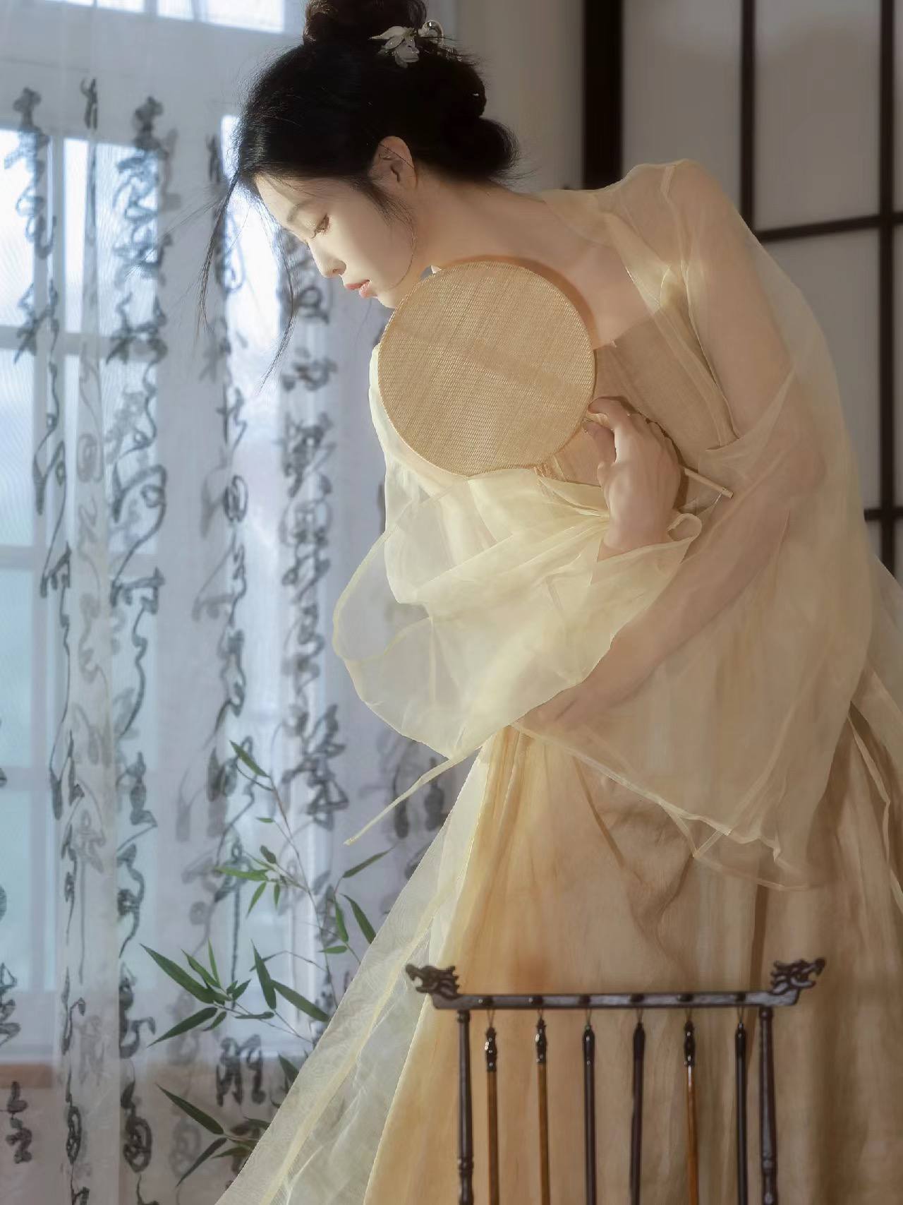 执团扇女子伫立书法窗前
