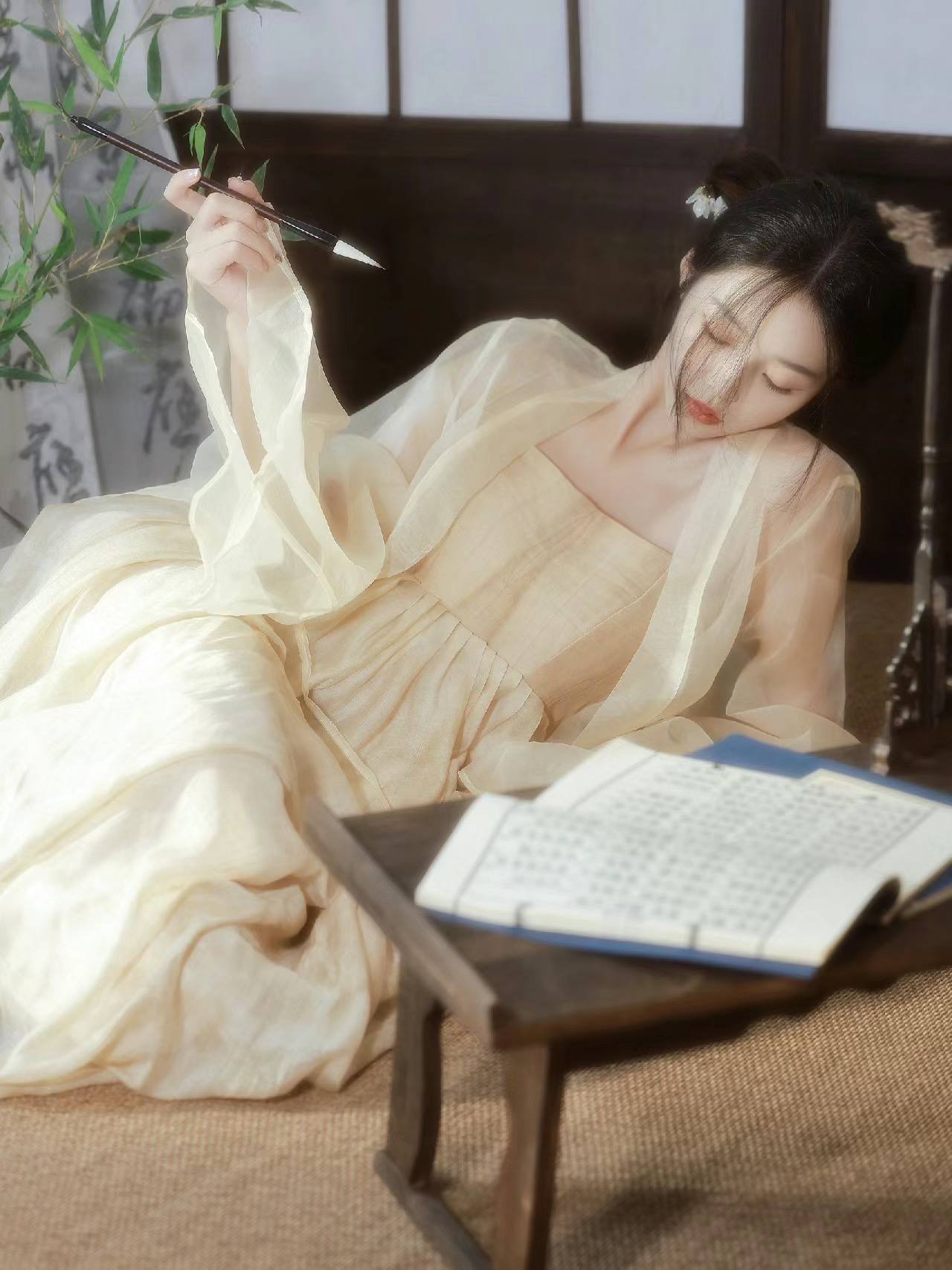 侧卧执笔女子与古籍竹影