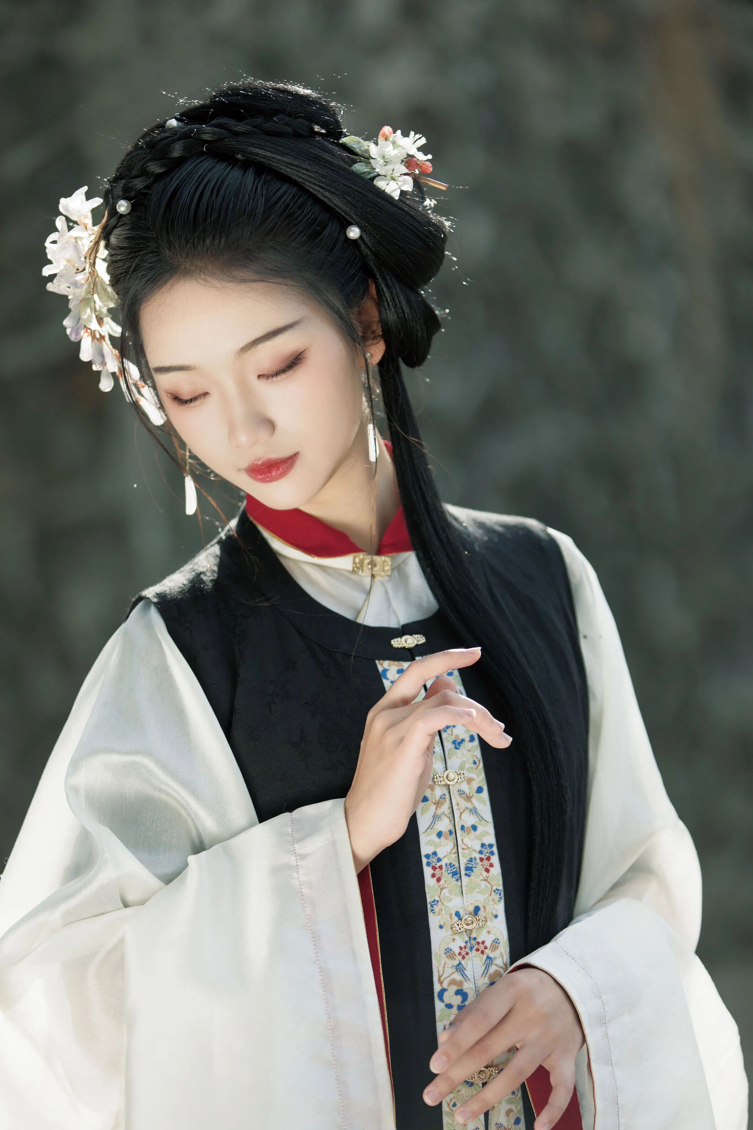 立于灰褐石墙前,垂眸轻捏