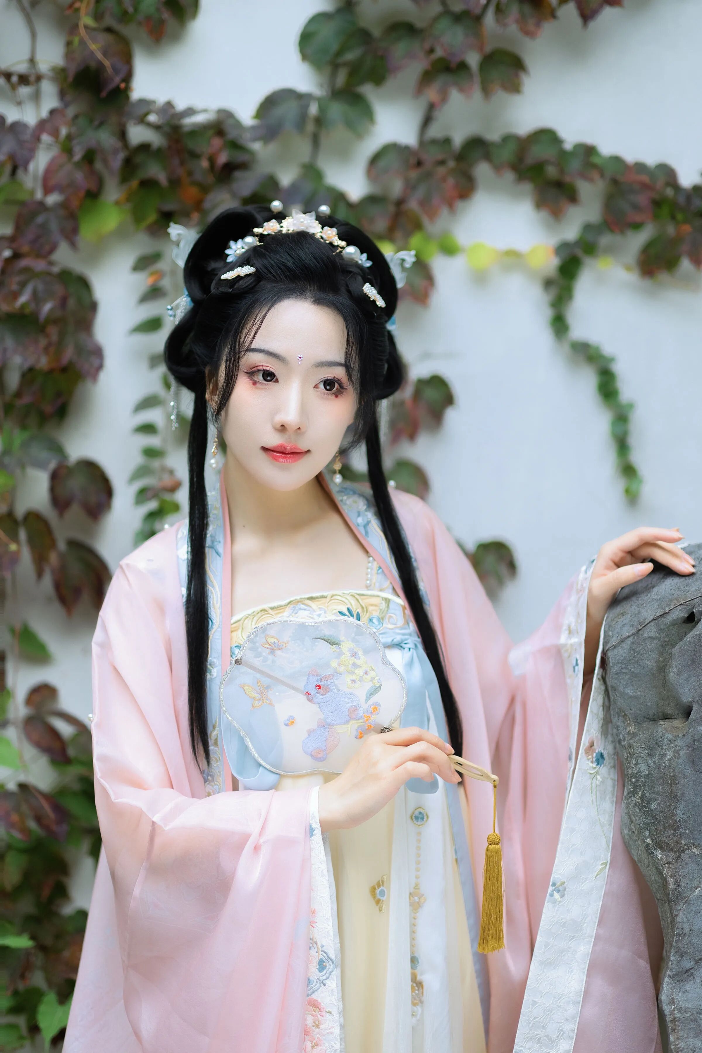 手持团扇轻靠石墩