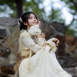 身着浅色汉服的女子坐在石阶上，手持弹弓，望向远方