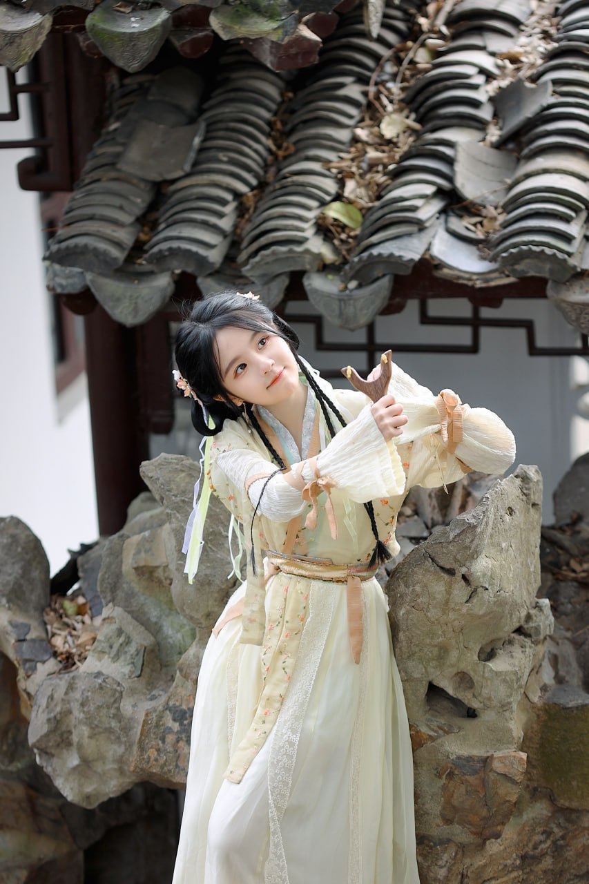 女子在假山前，手持弹弓